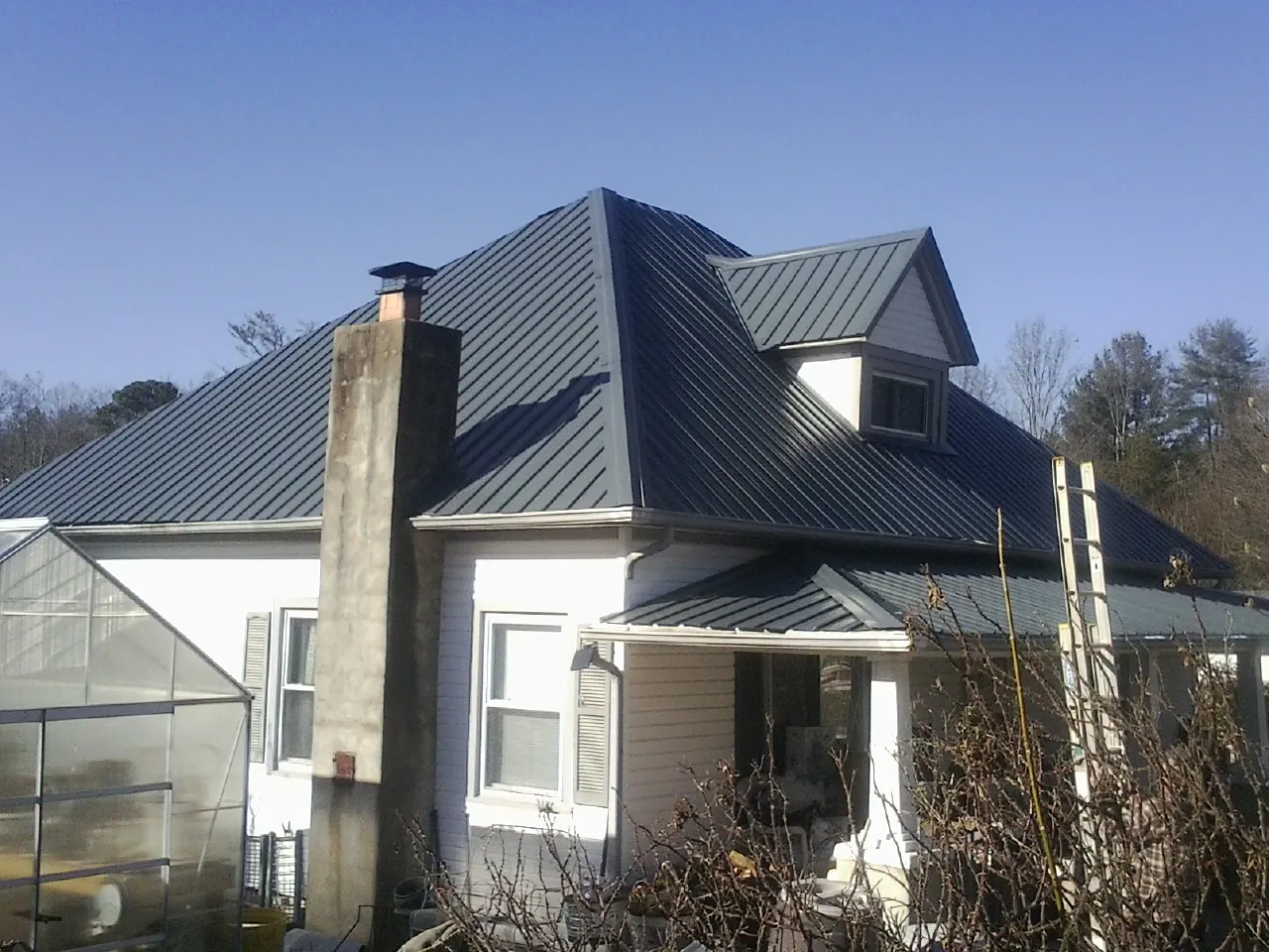 Dark blue standing seam metal roof on a white farmhouse with dormer — Slate & Tile Roof Repair by Roofing Brothers in Ragland