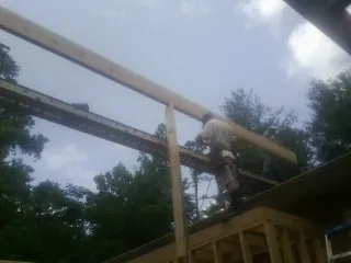 Carpenter setting a ridge beam over a new addition frame — Ice Dam Removal by Roofing Brothers in Ragland