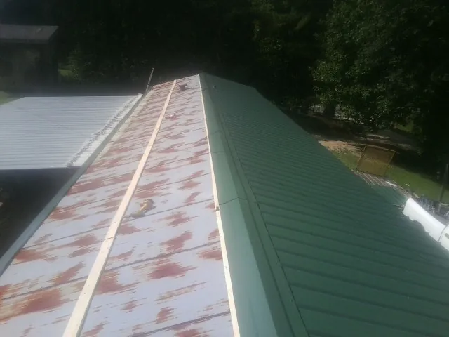 Old rusted panels beside newly installed green metal roofing — Wind Damage Roof Repair by Roofing Brothers in Ragland