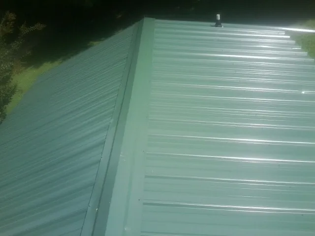 New green metal panels meeting at the ridge of a roof — Flat Roof Repair work by our crew in Ragland