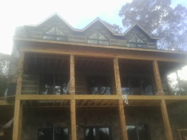 Dormers and porch framing on a large log home under construction — Roof Coating work by our crew in Ragland