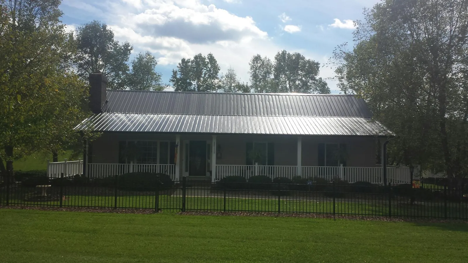 Gray metal roof on a brick ranch with a full width front porch — Gutter Guard Installation work by our crew in Ragland