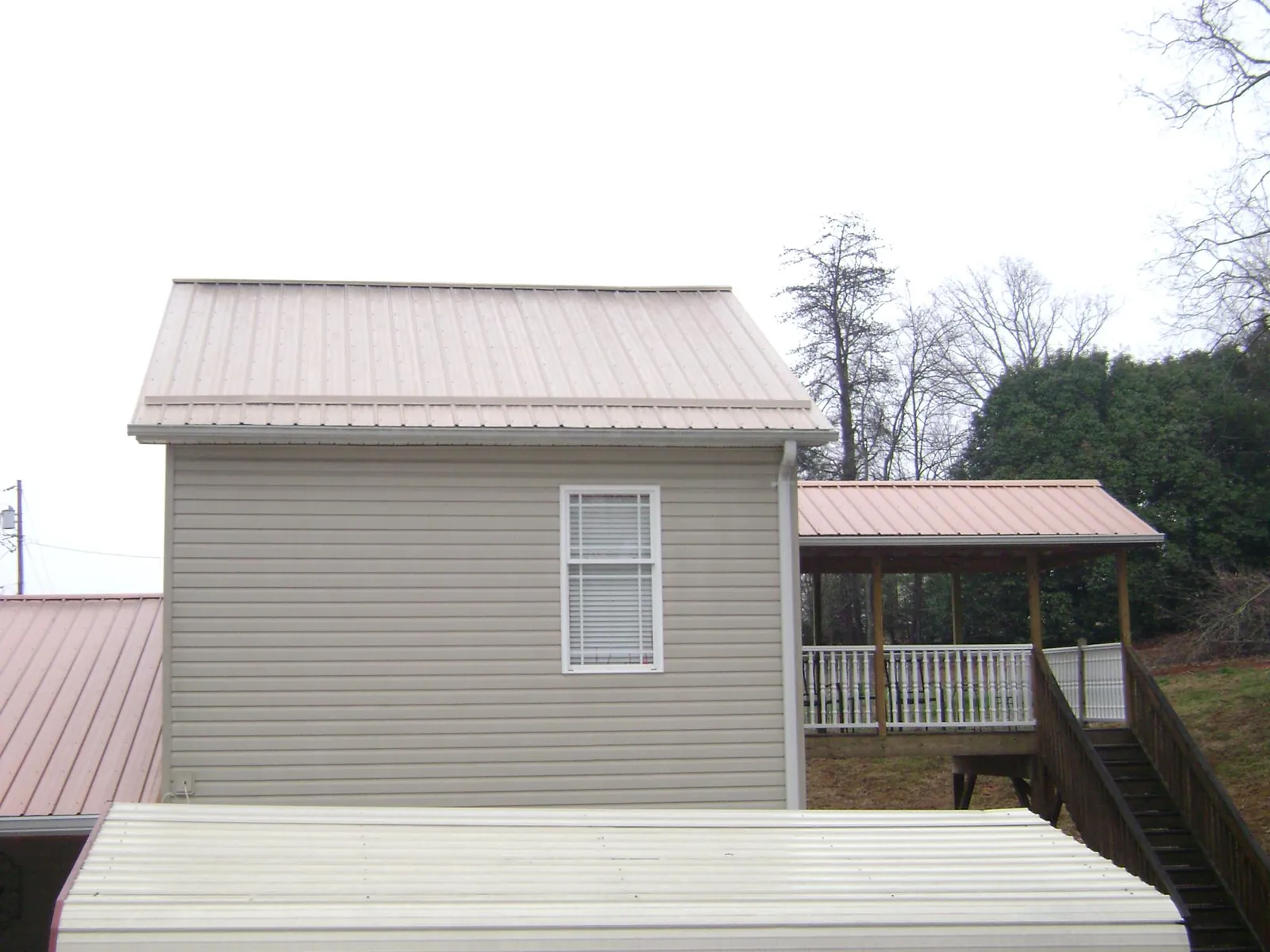 Tan metal roofs on a two story addition and attached porch, from a Roof Replacement job in Ragland