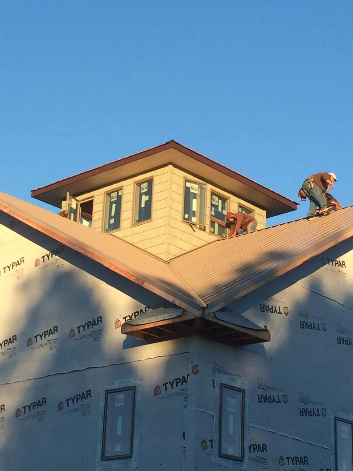 Roofers working around a rooftop cupola on a new metal roof at sunset — Roof Waterproofing in Ragland by Roofing Brothers